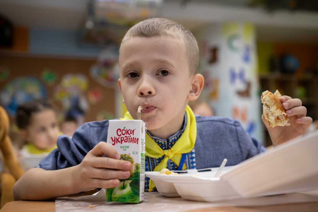 6-vuotias poika syö välipalaa pulpetin ääressä Ukrainassa.