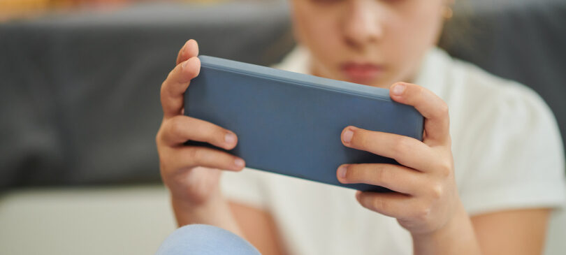 Lapsen kädet pitelevät puhelinta