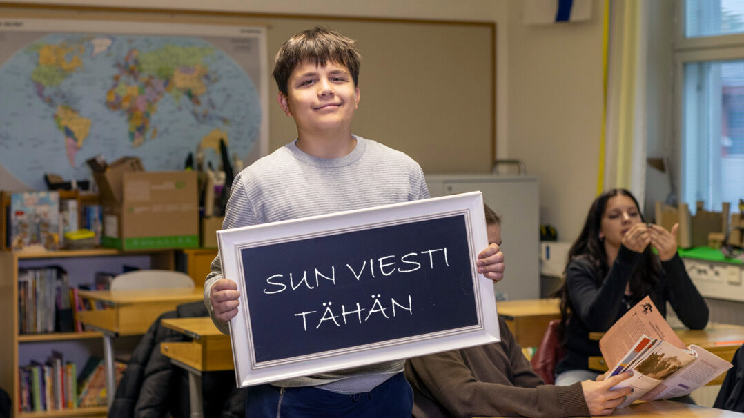Nuori pitää kylttiä, jossa lukee "sun viesti tähän".