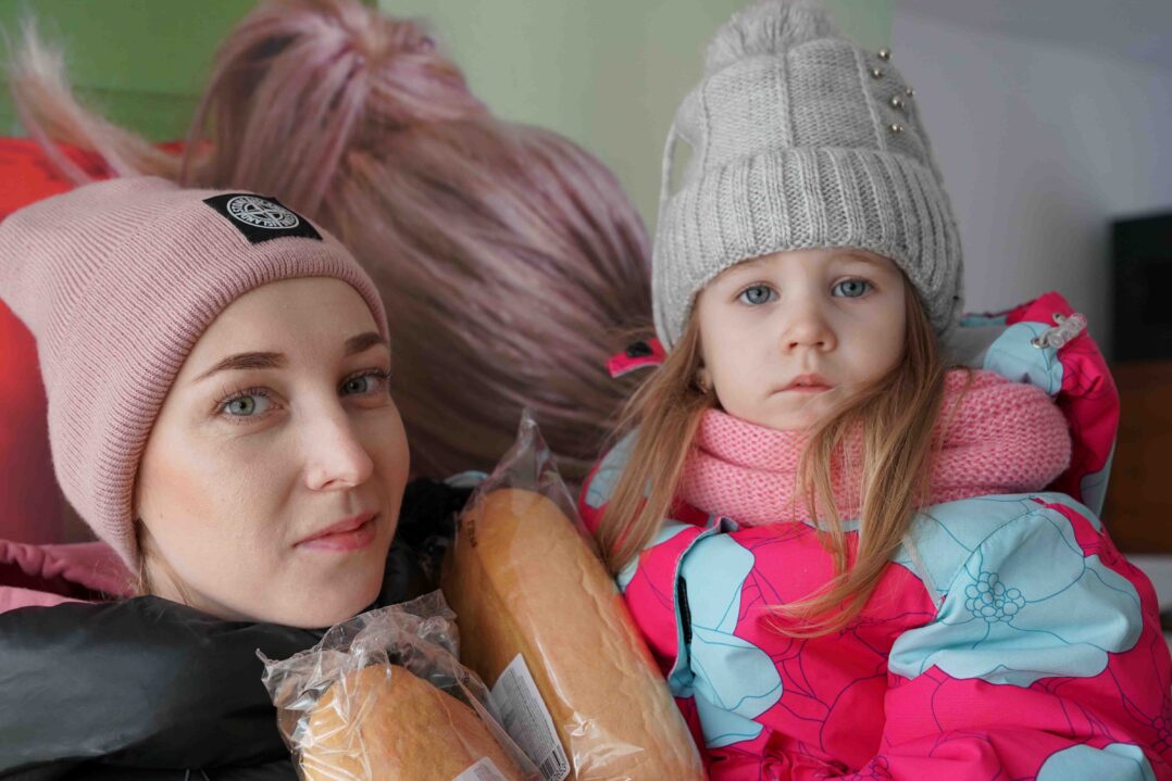 Ukrainalainen äiti ja 3-vuotias tyttö pitävät saamiaan leipäpaketteja.