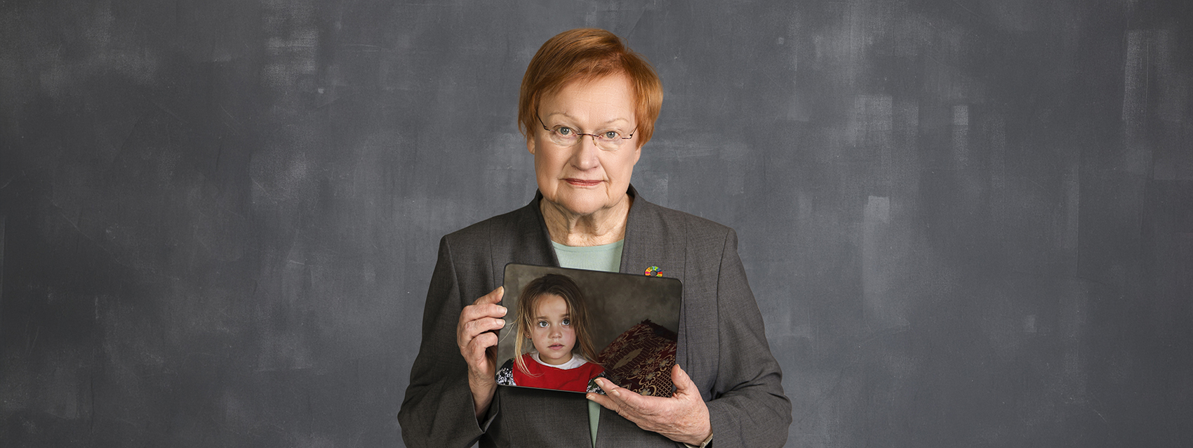Presidentti Tarja Halonen pitelee kädessään kuvaa lapsesta.