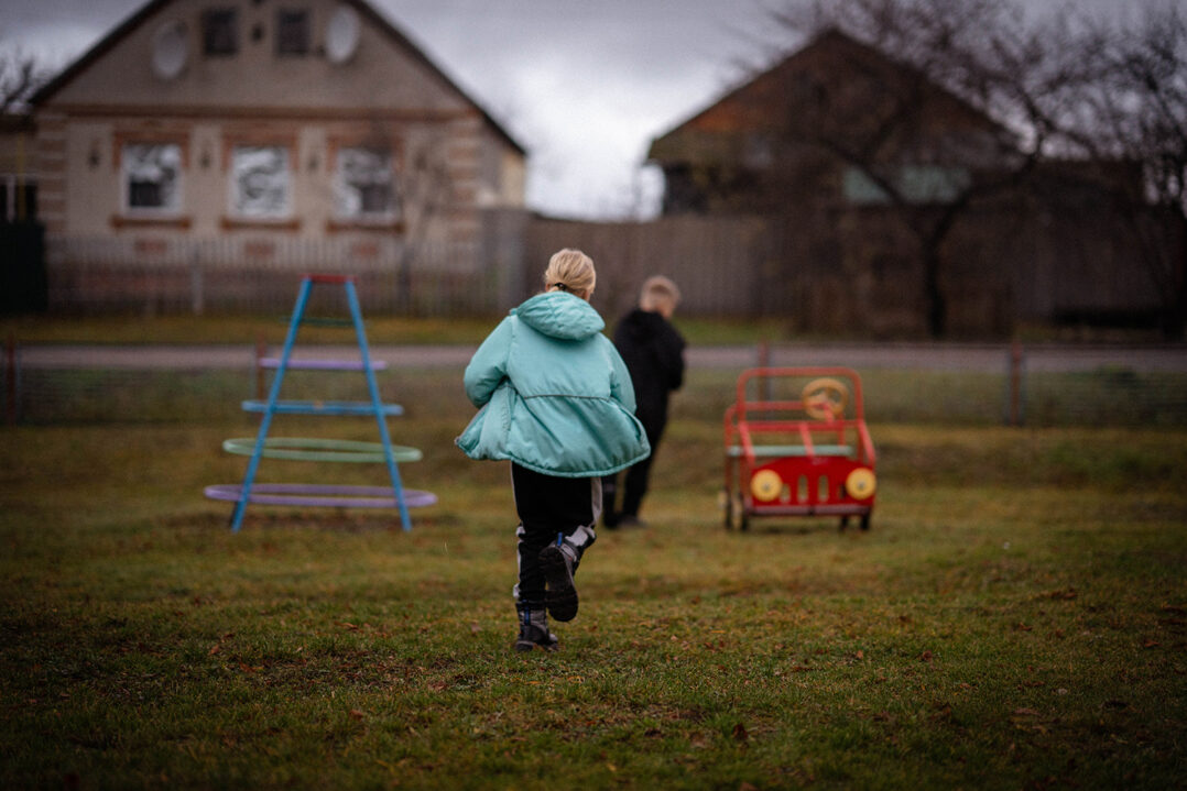 Lapset juoksevat poispäin, taustalla leikkipuiston välineitä.